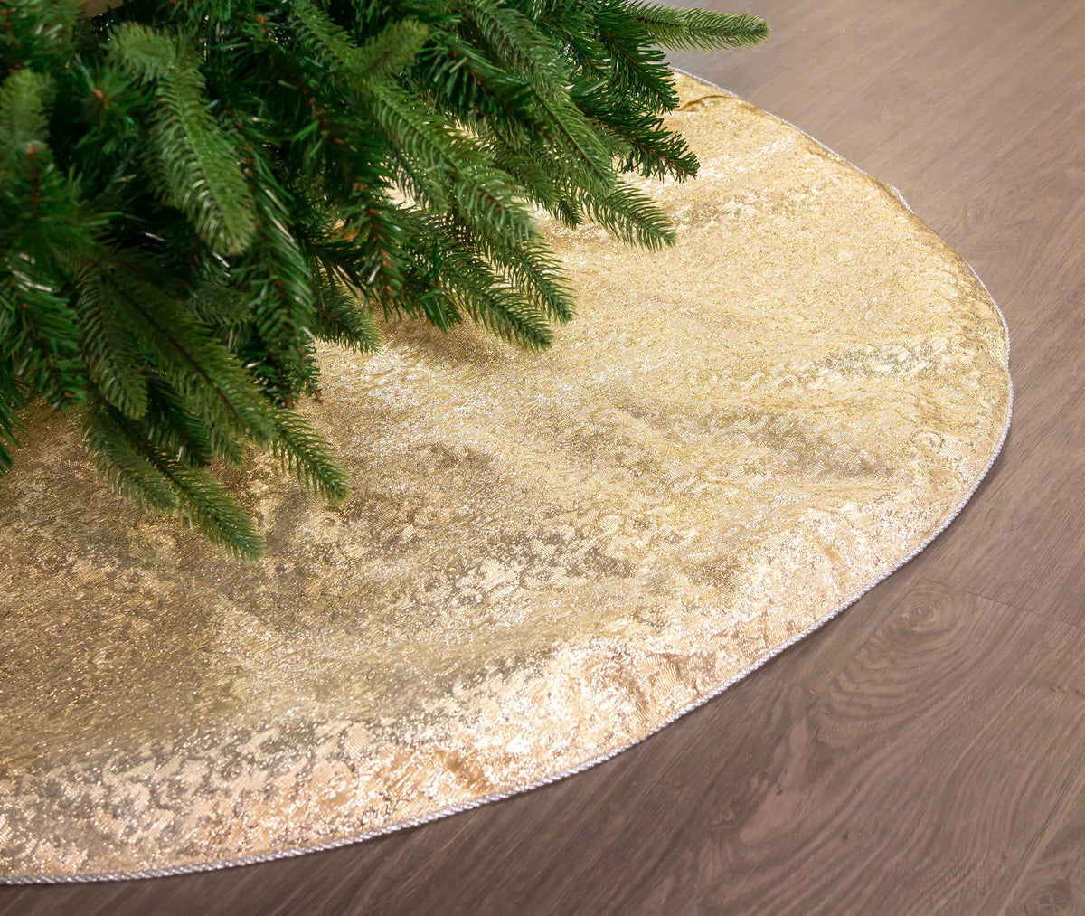 Gold glittery Christmas tree skirt with a tree on a wooden floor