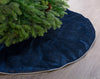 Navy blue Christmas tree skirt with a green tree on a wooden floor.