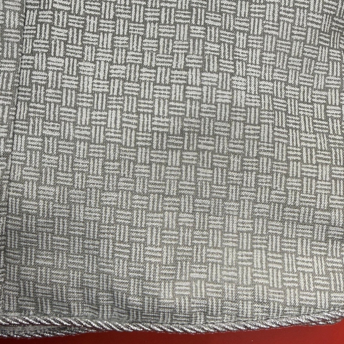 Close-up of a textured fabric with a geometric pattern on a red background