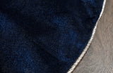 Close-up of a dark blue fabric with a gold edge on a wooden surface