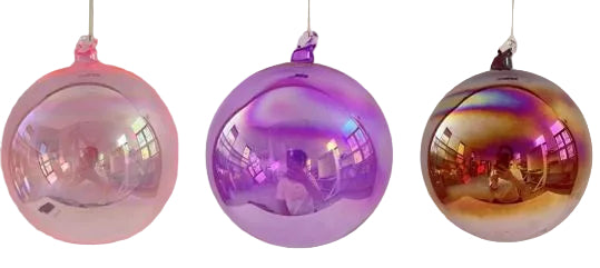 Three iridescent glass balls in pink, purple, and gold on a white background
