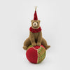 Stuffed bear in a clown outfit sitting on a red ball with a white background