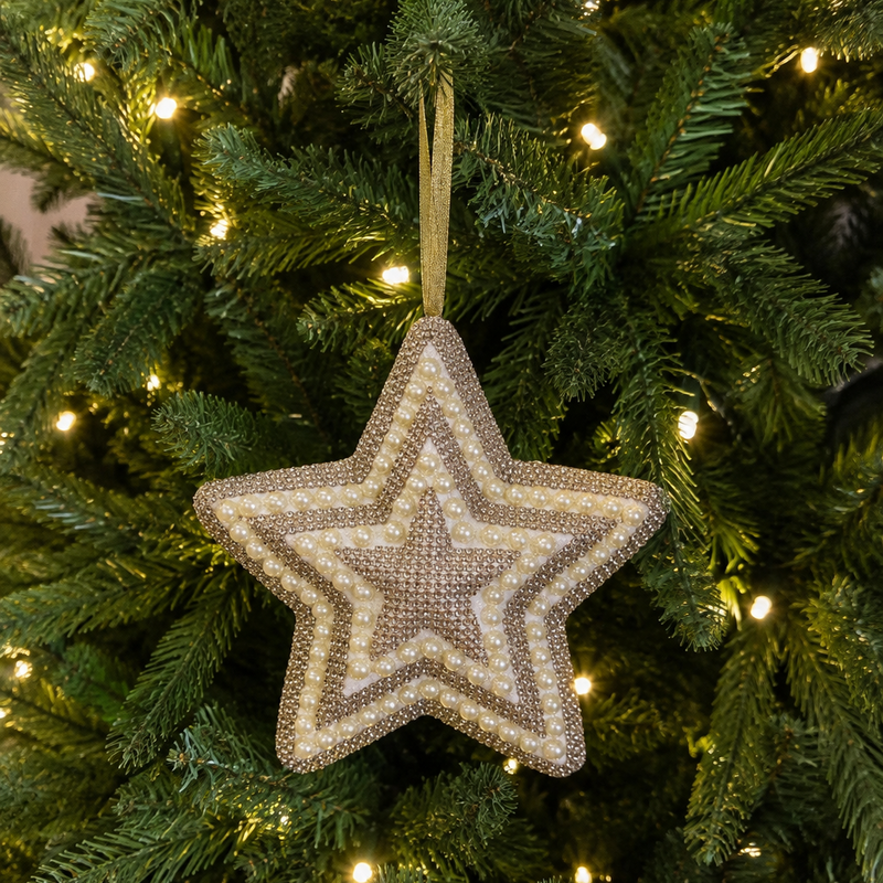 A textured, multi-layered star-shaped Christmas ornament in beige and brown tones hanging from a green Christmas tree with warm white lights.
