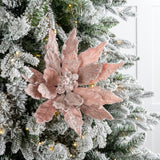 Decorative pink poinsettia on a Christmas tree with white lights.
