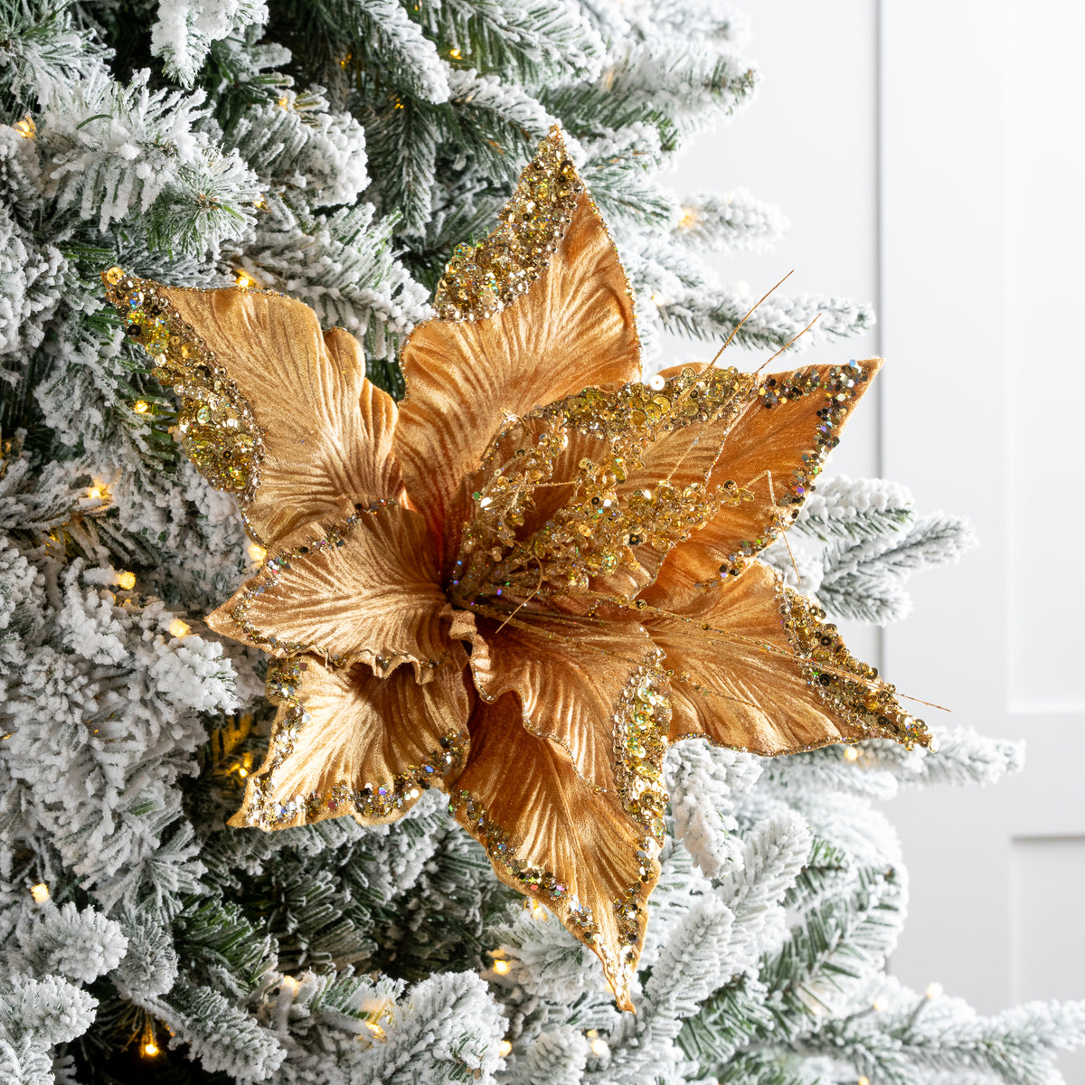 Decorative gold leaf ornament on a Christmas tree with snow effects