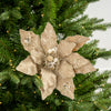 Decorative gold poinsettia ornament on a Christmas tree.