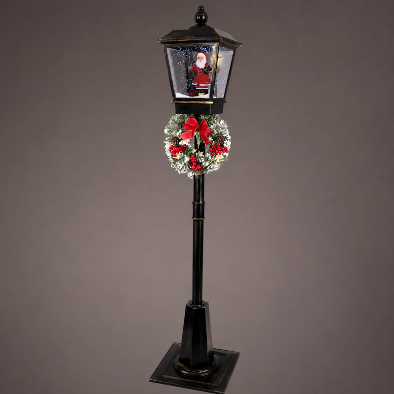 Decorative Christmas lamp post with a wreath and Santa Claus figure on a gray background
