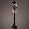 Decorative Christmas lamp post with a wreath and Santa Claus figure on a gray background