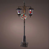 Decorative street lamp with Christmas wreath and Santa Claus figures on a brown background