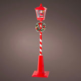 Decorative Christmas street lamp with candy cane design and wreath on a gray background