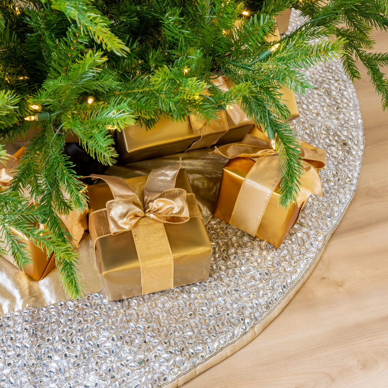 Gold gifts under a Christmas tree on a silver sequin tree skirt.