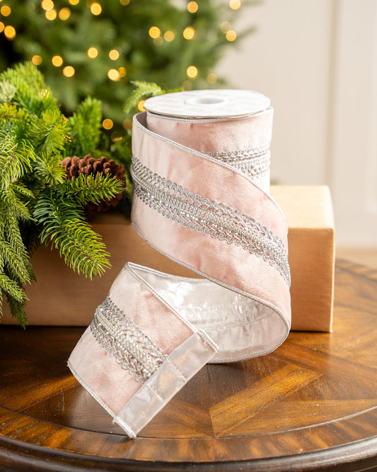 Decorative ribbon with silver accents on a wooden surface with a Christmas tree in the background