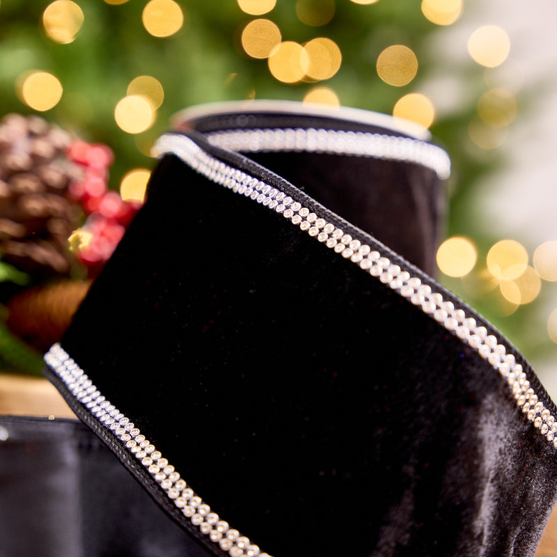 Black velvet pouch with silver trim against a blurred festive background