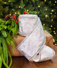 White decorative bow with ribbons on a brown box against a Christmas tree background