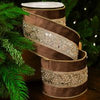 Decorative cylindrical object with ribbons and embellishments against a Christmas tree background