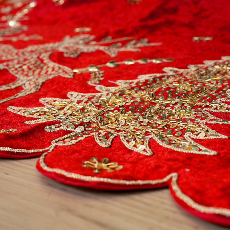 Close-up of red fabric with gold embroidery on a wooden surface