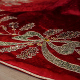 Close-up of red fabric with intricate silver embroidery on a wooden surface