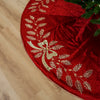 Red Christmas tree skirt with gold embellishments on a wooden floor.