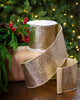 Gold glitter ribbon on a spool with a Christmas tree in the background