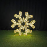 Decorative snowflake ornament with rhinestones on a green surface