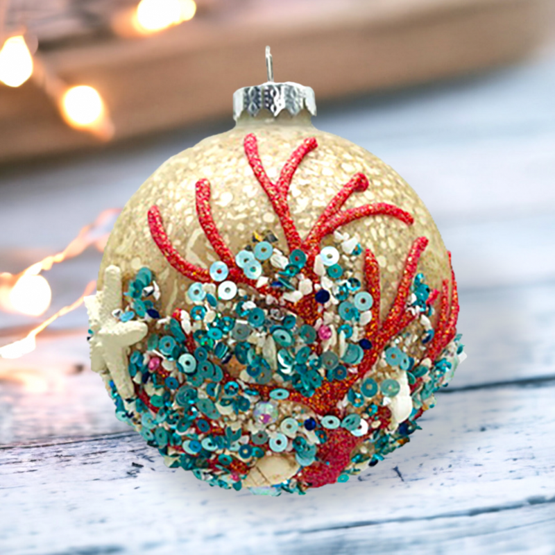 Decorative Christmas ornament with red and green coral-like patterns on a wooden surface.