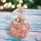 Decorative ornament with pink and white design on a wooden surface with blurred lights in the background