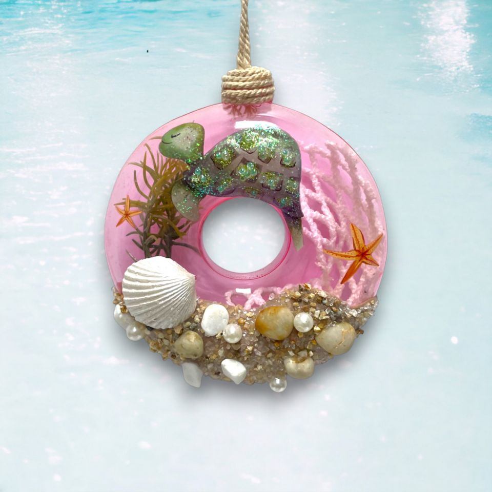 Decorative pink donut ornament with turtle, shells, and starfish on a light blue background