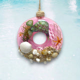 Decorative pink donut ornament with turtle, shells, and starfish on a light blue background