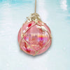 Decorative pink ornament with rope and pearls on a light blue background