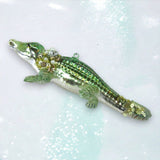 Decorative alligator ornament with beads on a glittery background