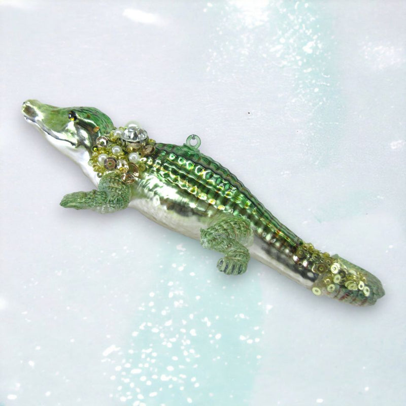 Decorative alligator ornament with beads on a glittery background
