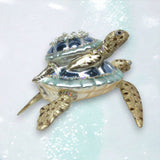 Decorative turtle figurine with gemstones on a light blue background