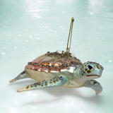 Decorative turtle ornament with embellishments on a light blue background