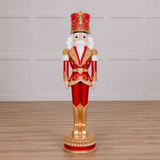 Decorative nutcracker figure in red and gold attire on a wooden floor.