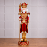 Decorative nutcracker figure in red and gold attire with a crown on a wooden floor.