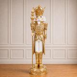 Decorative nutcracker figure in gold and white attire against a beige wall.