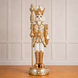 Decorative nutcracker figure with gold and white attire on a wooden floor.