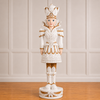 Decorative figure in intricate white and gold costume on a wooden floor with paneled wall background