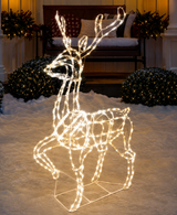 Decorative LED reindeer figure on a snowy ground with a warm glow, surrounded by festive decorations.