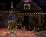 Decorative Christmas tree with multicolored lights in front of a house with string lights.