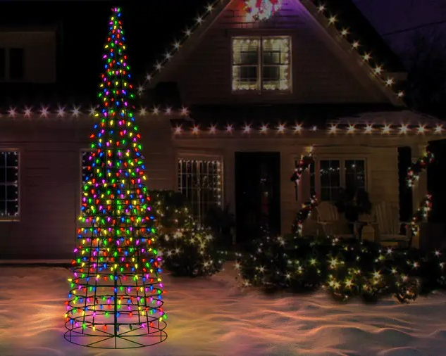 Decorative Christmas tree with multicolored lights in front of a house with string lights.