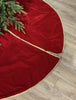 Red Christmas tree skirt with gold trim on a wooden floor