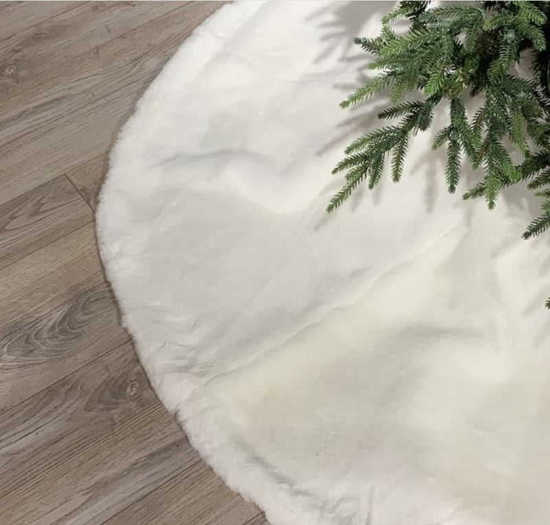 White tree skirt with green Christmas tree on a wooden floor