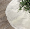 White tree skirt with green Christmas tree on a wooden floor