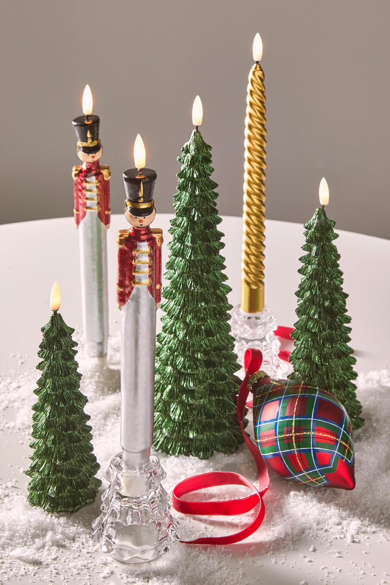 Decorative candles and Christmas ornaments on a snowy surface with a gray background