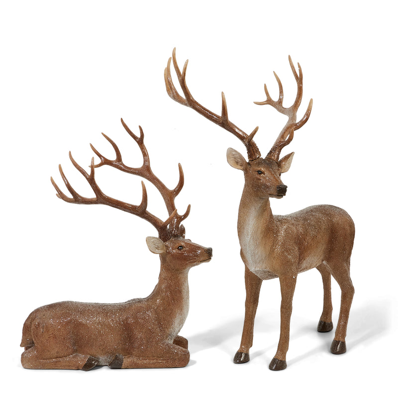 Two deer figurines, one standing and one lying down, on a white background