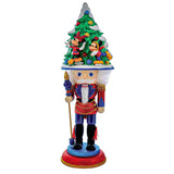 Decorative nutcracker with a Christmas tree on its head against a white background