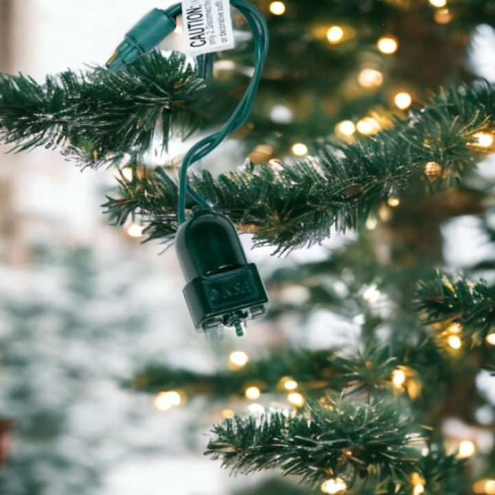 Christmas tree light plug on a branch with blurred lights in the background