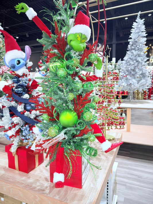 Decorative Christmas tree with ornaments and a Grinch figure in a store setting