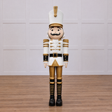 A large white and gold nutcracker soldier with a mustache, wearing a uniform and standing at attention.